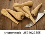 Parsnips roots and chefs knife on rustic wooden background