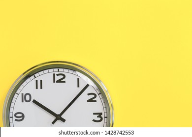 Part of analogue plain wall clock on trendy yellow background. Ten o'clock. Close up with copy space, time management or school concept and lunch time