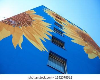 Part of an artistically painted house, skyscraper reaching for the sky, with huge sunflower blossoms on blue house wall, windows, mural painting, copy space - Shutterstock ID 1852398562