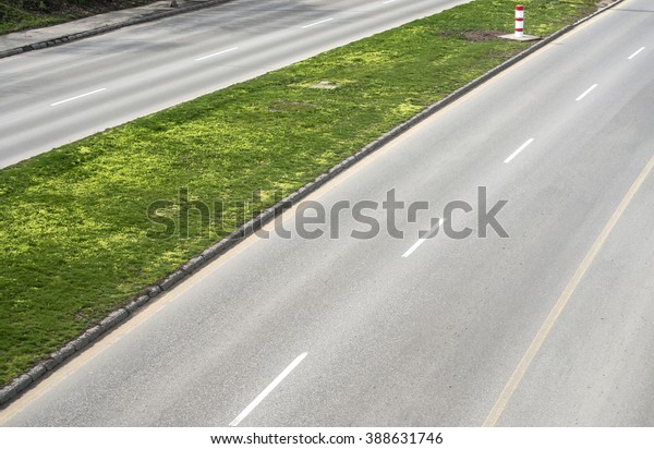 Part of asphalt motor road with dividing strip of\
green grass
