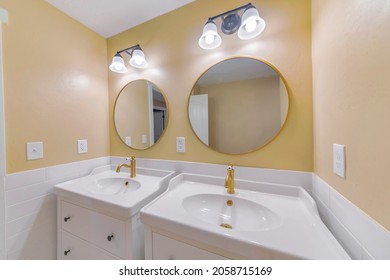 A Part Of A Bathroom Design With Two Sink And Vintage Round Mirror On The Wall With The Golden Frame 