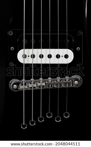 Part of a black electric guitar close-up.