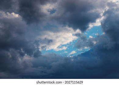 Part of blue sky look through frame of dark clouds. Beautiful natural air background.