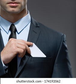 Part of body of man who takes out business card from the pocket of business suit, copyspace