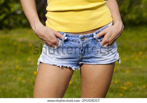 Part of the body, torn blue jeans shorts\
for women on the background summer\
street