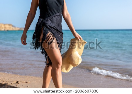 Part of the body of a woman walking along the seashore on a hot summer day.