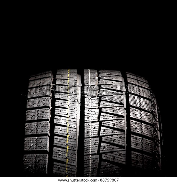 Part of brand new car tyre isolated on a black\
background. Square format.