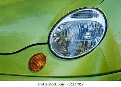 Part of car: headlamp and turn signal on green car.