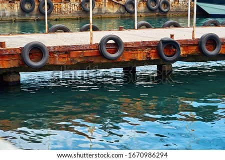 part closeup of old concrete sea berth or pier with car tires for mooring boats and yachts
