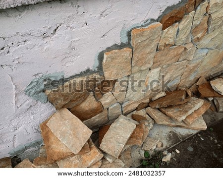 Part of the concrete foundation is lined with natural stone. Near the foundation of the house, there are many stones for facing the surface.