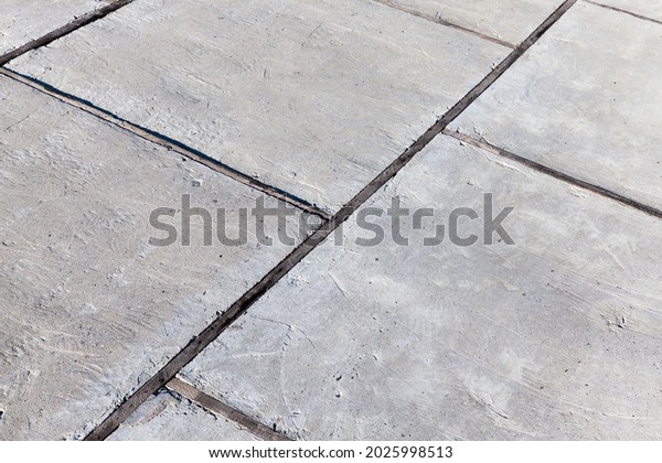 part of a concrete road\
made of concrete slabs, concrete slabs of the road divided by\
wooden boards