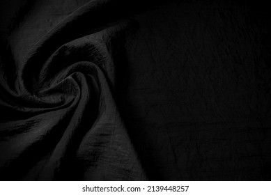 Part of the dark fabric texture of the fabric for the background and decoration of the work of art, a beautiful crumpled pattern of silk or linen. A crumpled piece of cloth
