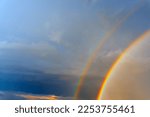 Part of a double rainbow on a background of bright clouds.