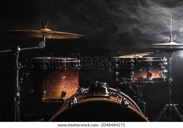 Part of a drum kit against a black\
background, percussion instrument, snare drum, bass drum, hi-hat on\
stage under the\
spotlights.