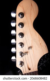 Part Of Electric Guitar Headstock Against Black Background.