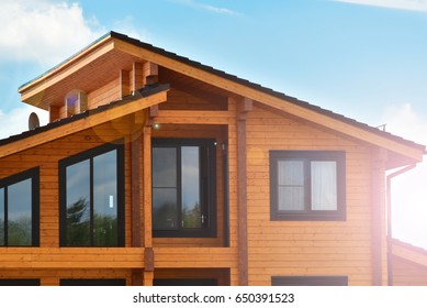 Part of the facade of a wooden house in modern style and sun rays