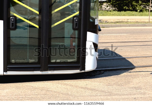 Part of front door of a fast moving in sunny city , eco\
driven autobuses in bus depot, part of city cheap safe public\
transport. 