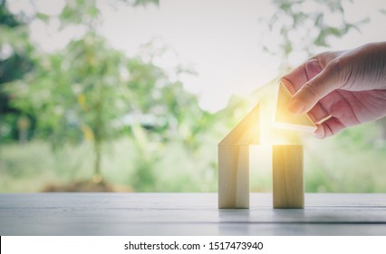 Part Of Human Hand While Building House From Natural Color Wooden Block