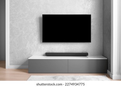 Part of the interior of the living room with a TV on the wall, hifi equipment, Sound bar, gray cabinet. TV and music system in the interior. Modern living room. Minimalism in the interior.