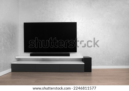 Part of the interior of the living room with a TV on the wall, hifi equipment, Sound bar, gray cabinet. TV and music system in the interior. Modern living room in bright colors. Minimalism interior.