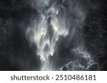 Part of a magnificent large waterfall as a dreamy, almost abstract high contrast image. White water on dark cliffs.