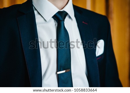 The part man in a suit, shirt, tie, silver buckle on tie. stylish classic menswear. A businessman prepares in the morning for a business day or groom in a wedding.
