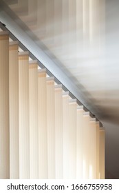 Part of the mechanism of beige vertical blinds on the background of a mirror stretch ceiling.