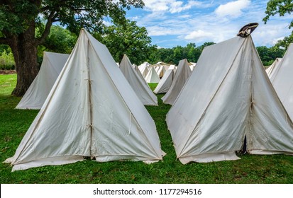 Part Of Military Camp At A Reenactment Of The American Revolutionary War (1775-1783), With A Tricorne Hat (for Man Or Woman) On Top Of One Of Many White Tents, For Motif Of Difference Or Individuality