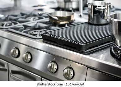 Part Of A Modern Kitchen In The Restaurant Or Hotel With Professional Equipments - Steel Gas Cooker, Pots And Pans ( Low DOF)