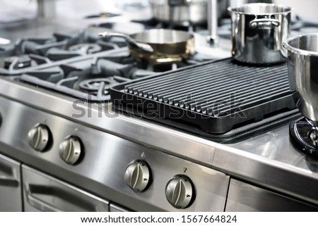 Part of a modern kitchen in the restaurant or hotel with professional equipments - steel gas cooker, pots and pans ( low DOF)