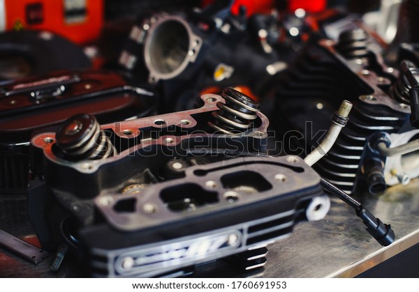 Part of a motorcycle\
engine on a table in a workshop, motorcycle valve, motorcycle and\
car service concept
