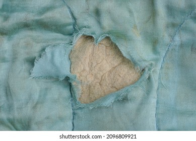 Part Of An Old Blanket Made Of Dirty Blue Cloth With A Torn Hole And Gray Cotton Wool