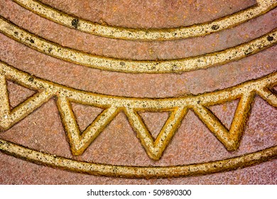 part of old metal rusty manhole cover with long parallel lines and zigzag in a circle toned to gold color, rainbow picture on metal manhole with recess and rusty parts, top view of metal manhole part - Powered by Shutterstock