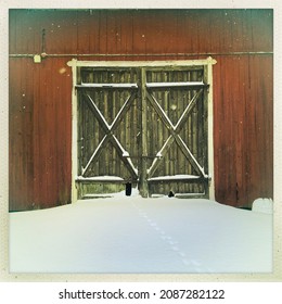 Part Of An Old Red Barn With Brown Wooden Doors And Lots Of Snow