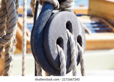 Part of an old sailing wooden ship with pulleys, knotted ropes and wooden fasteners. Rigging on an old wooden ship. Old ship pulley