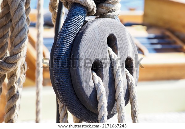 Part of an old sailing wooden ship with pulleys,\
knotted ropes and wooden fasteners. Rigging on an old wooden ship.\
Old ship pulley
