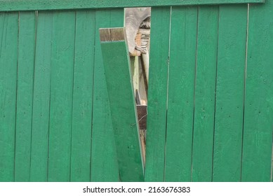 Part Of An Old Wooden Green Fence Wall With A Broken Plank On A Rural Street