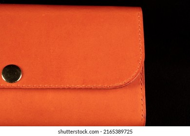 Part Of An Orange Leather Wallet On A Dark Background.