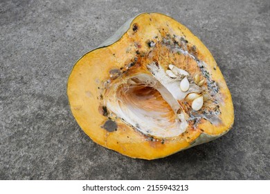 Part Of An Orange Pumpkin Starting To Rot. Pumpkin On A Concrete Background.