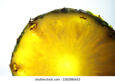 A part of a pineapple slice with a light behind it.
