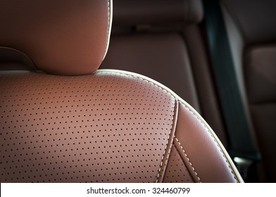 Part Of Red Leather Car Seat With The Unfocused Car Interior On The Background