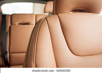 Part of red leather car seat with the unfocused car interior on the background