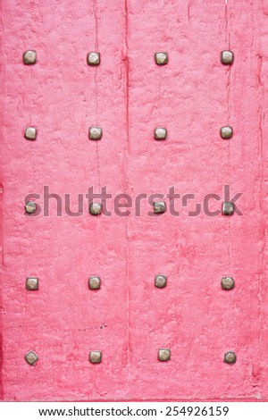 Part of a red medieval door with metal studs
