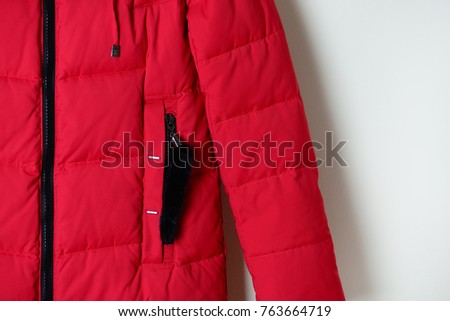 Part of red winter down jacket with a pocket on the zipper. Fashion clothes. Outerwear. Macro.