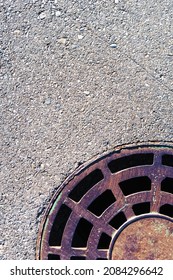 Part Of A Round Manhole With Grating On The Asphalt. View From Above