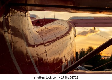 Part Of The Shiny Hull Of A Red Small-passenger Plane In Sunset Light