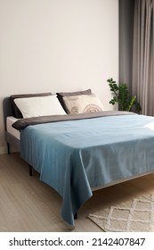 Teil eines geräumigen, komfortablen Schlafzimmers mit Doppelbett in der Mitte mit zwei handgefertigten pastellfarbenen Kissen und einer hellblauen Decke – Stockfoto