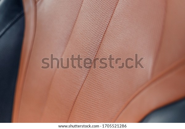 Part of stitched leather brown\
leather car interior. Modern luxury car black and brown perforated\
leather interior. Car leather interior details. Decorative\
seam