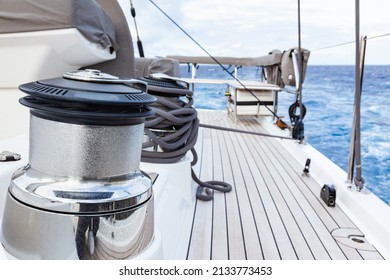 Part Of The Teak Deck Of A Sailing Yacht With Bollards And Sail Winches For Fixing The Sail Ropes.