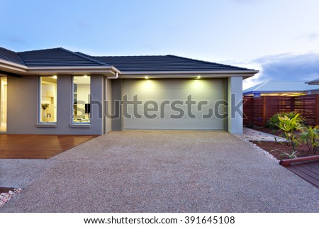 Part of this luxury house includes a garage with a white door and illuminated by two small lights under the ceiling.